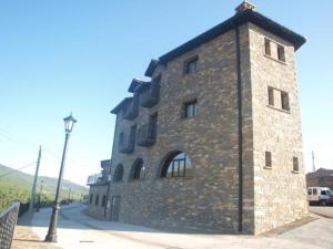 a large brick building on the side of a street at Apartamentos Pirineos Ordesa in El Pueyo de Araguás