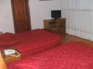 a hotel room with two beds and a television at Residencial Pinto in Guarda