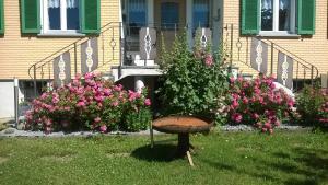 a birdbath in the grass in front of a house with flowers at Bio-Bauernhof Heidegger in Möggers