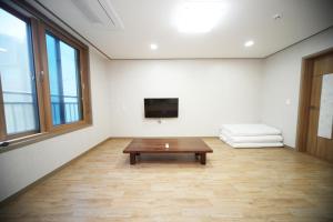 a living room with a coffee table and a flat screen tv at Seongsan Star Pension in Seogwipo