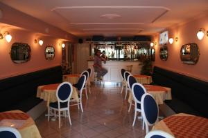 a woman standing in a restaurant with tables and chairs at Apartman Bella Hotel in Siófok