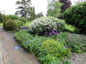 un jardin fleuri et un chemin en briques dans l'établissement Chambre d'hotes de la Vallee, à Montaure