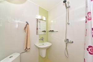 a white bathroom with a sink and a shower at Lazur Studio in Burgas City