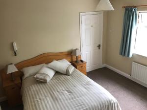 a bedroom with a bed with two pillows and a window at Derreen Tighue House in Tralee