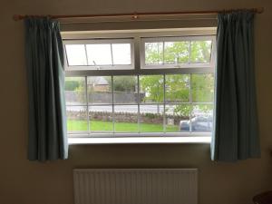 a window with blue curtains and a radiator at Derreen Tighue House in Tralee