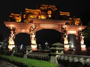 un portail de nuit avec des statues sur celui-ci dans l'établissement Peace Inn The Leshan Giant Buddha Branch, à Leshan