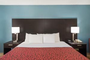 um quarto com uma cama com 2 candeeiros e um telefone em Days Inn by Wyndham Raleigh Midtown em Raleigh