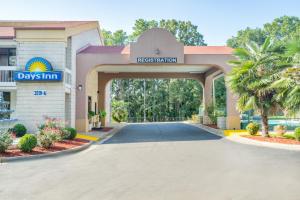 um edifício com um portão com uma placa que lê dias pousada em Days Inn by Wyndham Raleigh Midtown em Raleigh