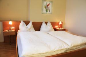 a large bed with white sheets and pillows at Beim Gangl in Illmitz