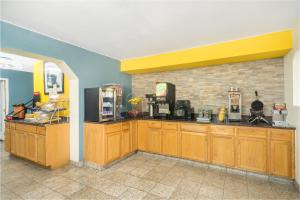 a kitchen with wooden cabinets and a brick wall at Days Inn by Wyndham Raleigh Midtown in Raleigh