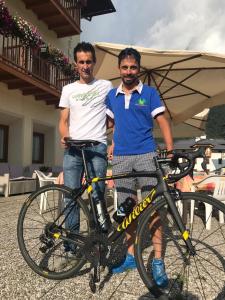 two men are standing next to a bike at Hotel Serenella in Canale San Bovo