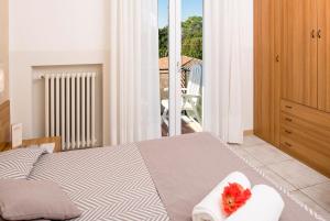 a bedroom with a bed with towels and a balcony at Hotel Taormina in Bardolino
