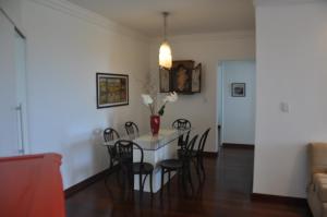 una mesa de comedor con sillas y un jarrón con flores en 3 Quartos na Praia do Buracão - Rio Vermelho, en Salvador