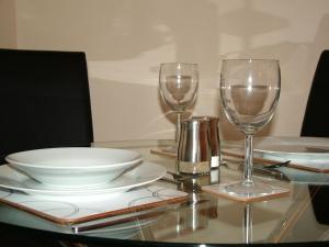 a table with two wine glasses and plates on it at Stratford Apartment in Newmarket +7 photos