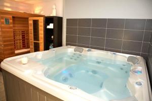 El baño incluye una gran bañera azul. en Le Bretagne - Hôtel Spa & Sauna, en Douarnenez