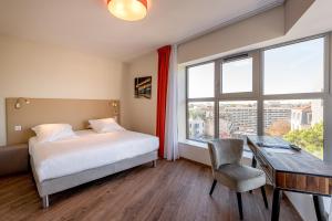 1 dormitorio con cama, escritorio y ventana en All Suites Bordeaux Marne – Gare Saint-Jean, en Burdeos