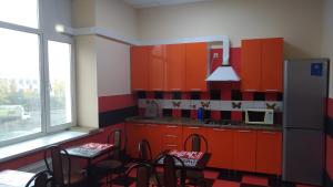 a kitchen with orange cabinets and chairs and a refrigerator at Mini Hotel Tarleon in Moscow