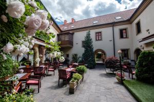 un patio esterno con tavoli, sedie e fiori di Hotel Octarna - Free parking a Kroměříž