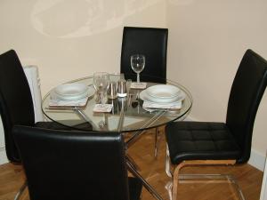 una mesa de cristal con sillas y copas de vino. en Stratford Apartment en Newmarket