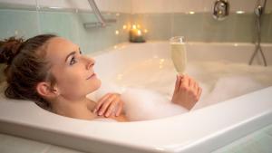 a woman in a bathtub with a glass of champagne at Alpenblick in Zermatt +37 photos