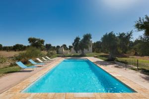 a swimming pool with lounge chairs next to a house at Casale Cimino by BarbarHouse in Ostuni