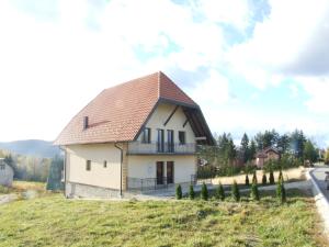 a small white house with a brown roof at Apartmani Tarsko Sunce in Kaludjerske Bare