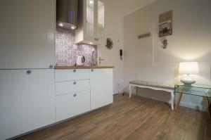 a kitchen with white cabinets and a bench in it at Blue Boat Apartment Sopot in Sopot