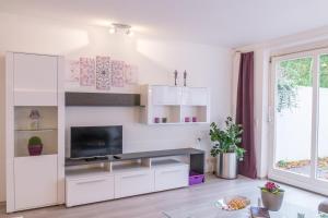 a living room with white cabinets and a flat screen tv at Ruhiges und zentral gelegenes Apartment in Rosenfeld