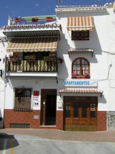 ein weißes Gebäude mit zwei Balkonen und einem Geschäft in der Unterkunft Apartamentos Isabel in Maro