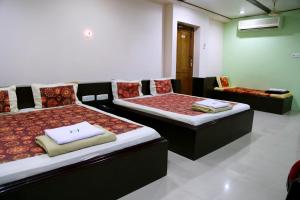 CuddaloreHotel Suriyapriya的有两张床和一张沙发的酒店房间 更多21张照片