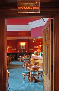 a restaurant with tables and chairs and a bar at Ramnee Hotel in Forres