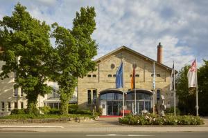a building with flags in front of it at H4 Hotel Residenzschloss Bayreuth in Bayreuth