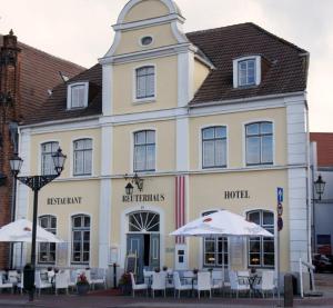 a building with tables and umbrellas in front of it at Hotel Reuterhaus Wismar in Wismar