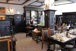 a woman sitting in a restaurant with tables and chairs at Hotel Reuterhaus Wismar in Wismar