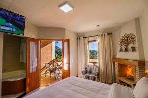 a bedroom with a bed and a fireplace and a television at Pousada Suiça Mineira Centro in Monte Verde +37 photos