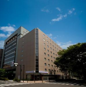 a large building on a street with a blue sky at Daiwa Roynet Hotel Shin-Yokohama in Yokohama