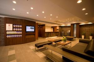 a hotel lobby with couches and tables and a tv at Daiwa Roynet Hotel Shin-Yokohama in Yokohama