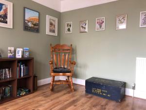 a wooden chair sitting in a room with a book shelf at Burlington House Guest House in Hunstanton