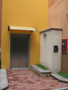 a building with a gray door and a yellow wall at Albergo Hotel Giardino in Desio