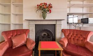 ein Wohnzimmer mit 2 roten Stühlen und einem Kamin in der Unterkunft Shrimp Terrace in Sheerness