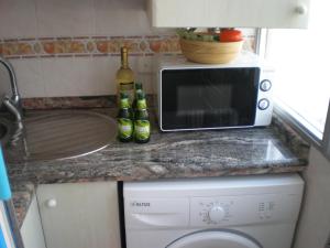 una encimera de cocina con microondas y lavadora en Apartamento Antillas, en Gandía