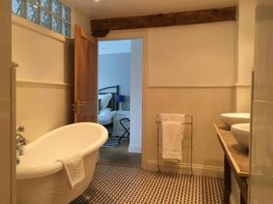 La salle de bains est pourvue d'une baignoire, de deux lavabos et de toilettes. dans l'établissement Stoneleigh Barn Bed and Breakfast, à Sherborne