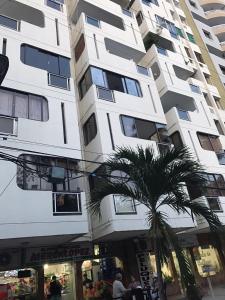 ein hohes Gebäude mit einer Palme davor in der Unterkunft Lindo Apartamento en Rodadero Santa Marta in Santa Marta