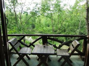 a picnic table on a porch with a view of a forest at Marisa Resort & Spa Chiang Dao in Ban Muang Ngai