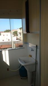 baño con lavabo blanco y ventana en Kitnetes Mar Azul, en Arraial do Cabo