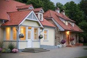 uma casa com um telhado vermelho em Botique & SPA Hotel Berkenes Manor em Ziedkalne