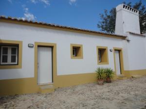 un edificio blanco y amarillo con plantas delante en Monte da Amoreira en Elvas