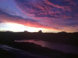a sunset over a lake in the mountains at Achmelvich View self catering in Lochinver