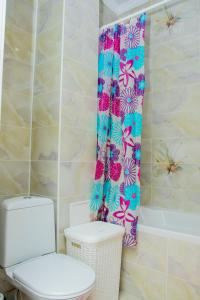 a bathroom with a toilet and a shower curtain at Apartments Manghilik El 53/66 in Astana