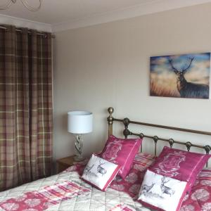 a bedroom with a bed with pink pillows at Achmelvich View self catering in Lochinver